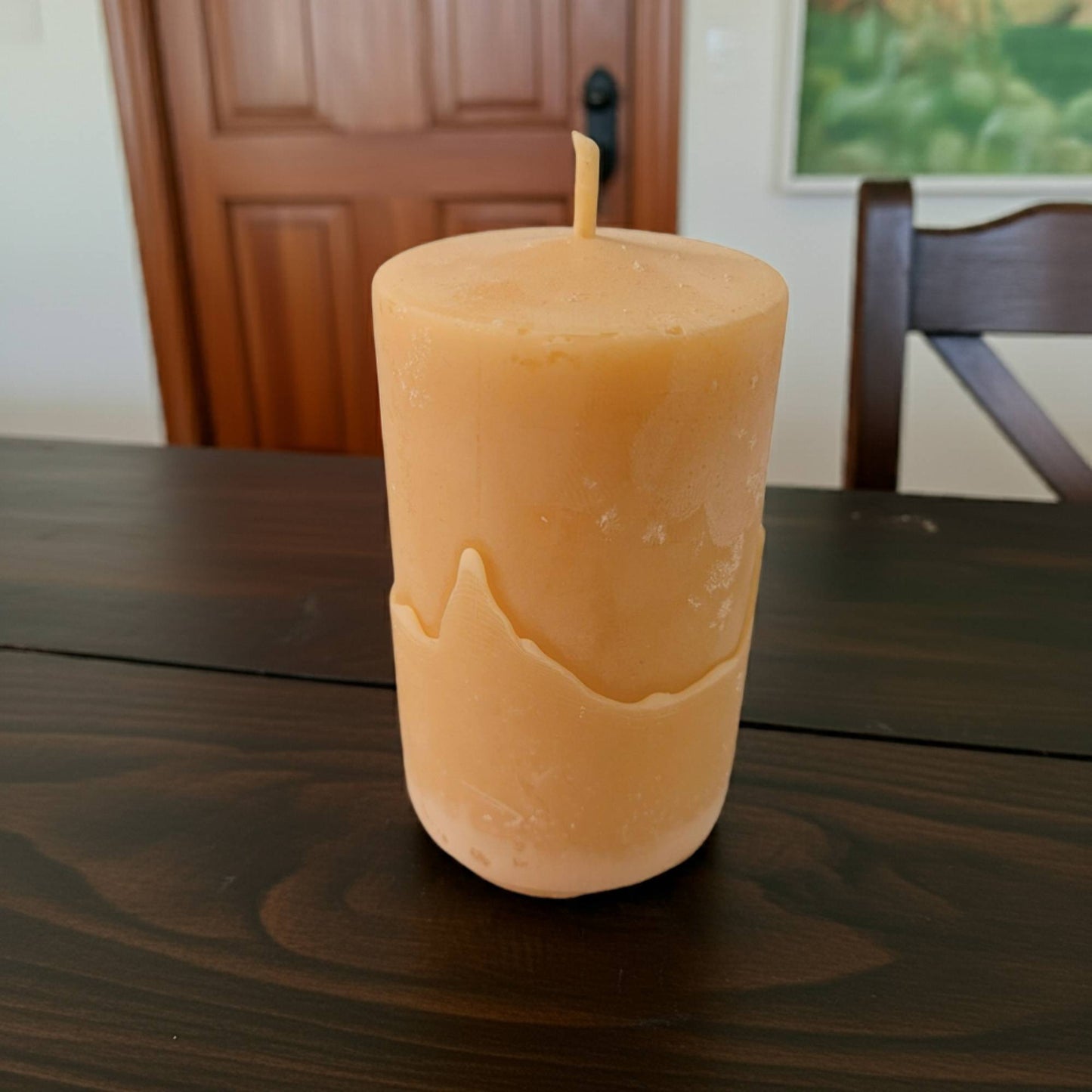 2x3 smooth pillar beeswax candle on a wooden table with a blurred background