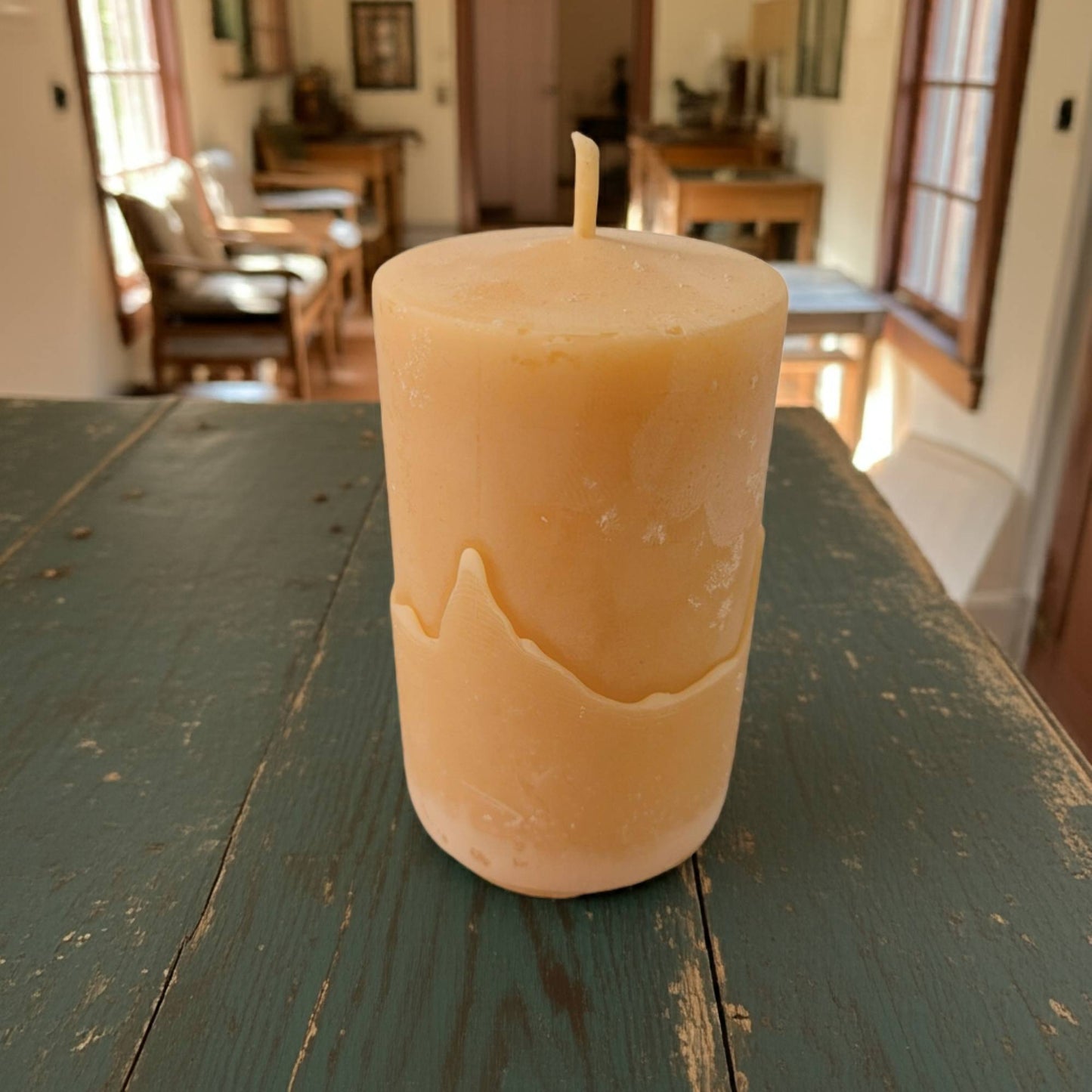 smooth pillar candle on a wooden table with a room in the background
