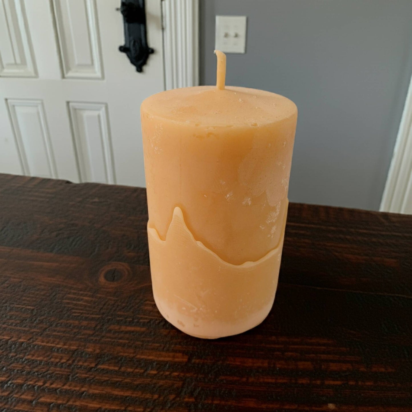 2x3 pillar beeswax candle on a wooden surface with a neutral background