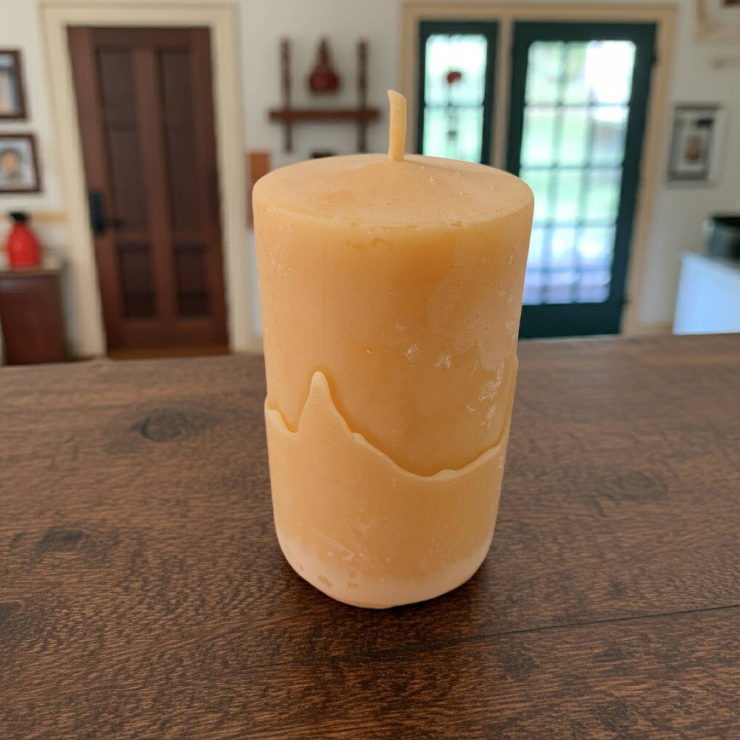 beeswax candle on a wooden table with a blurred indoor background