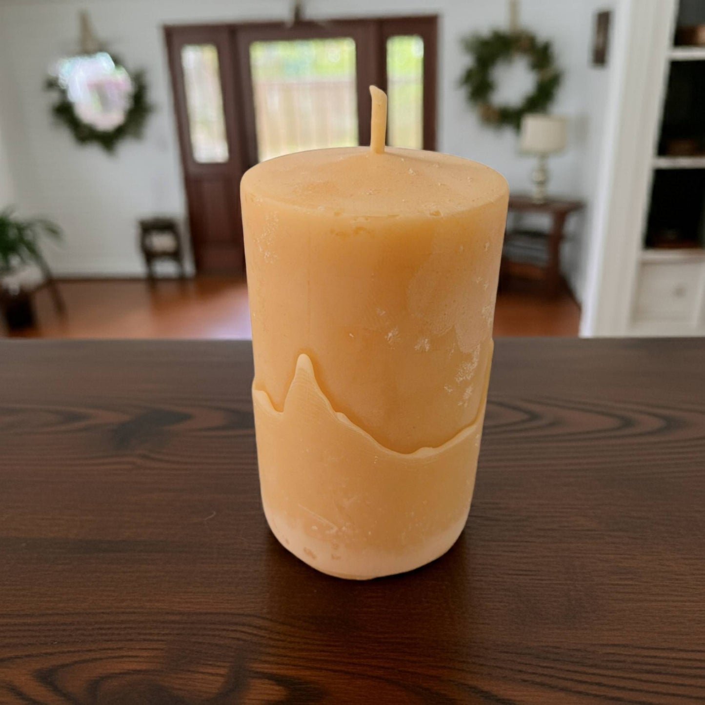 smooth pillar candle on a wooden table with a blurred indoor background