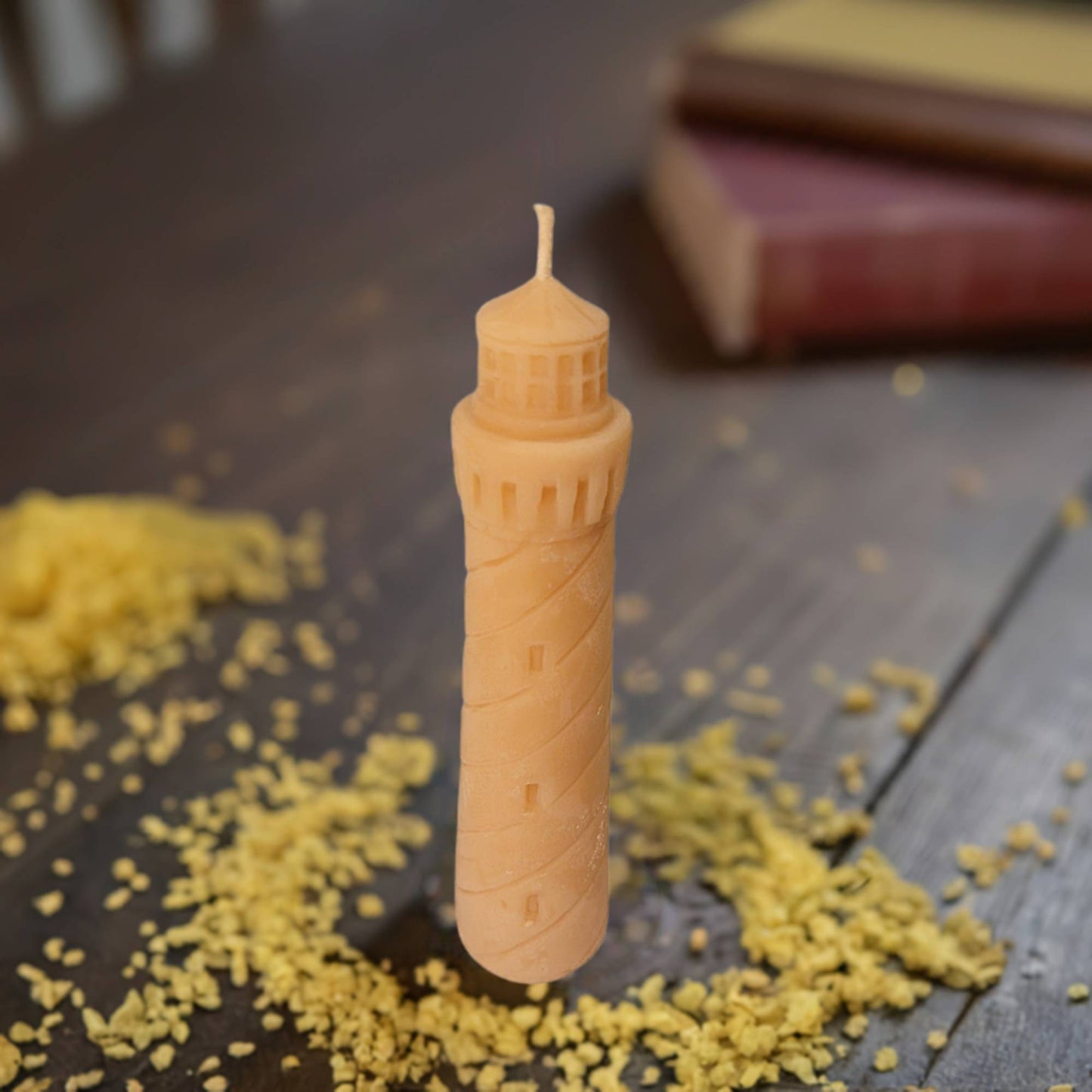 Candle shaped like a lighthouse tower on a wooden surface with yellow candle wax.
