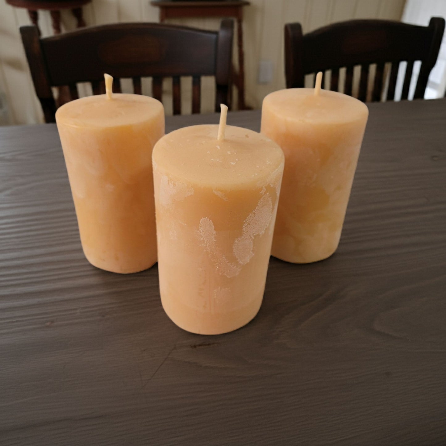 Three 2x3 smooth pillar beeswax candles on a rustic wooden table.