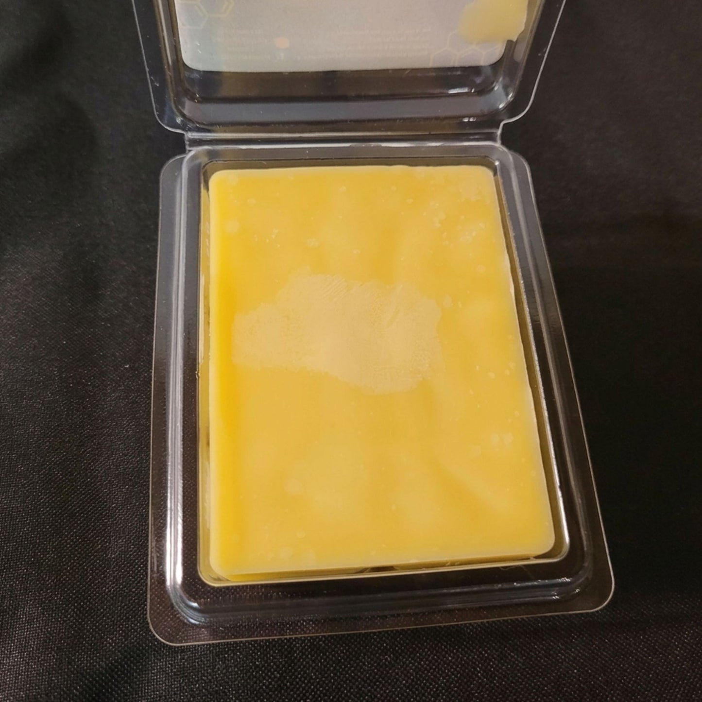 An open package of pure beeswax sweet orange scented wax melt from sticky bee apiary.