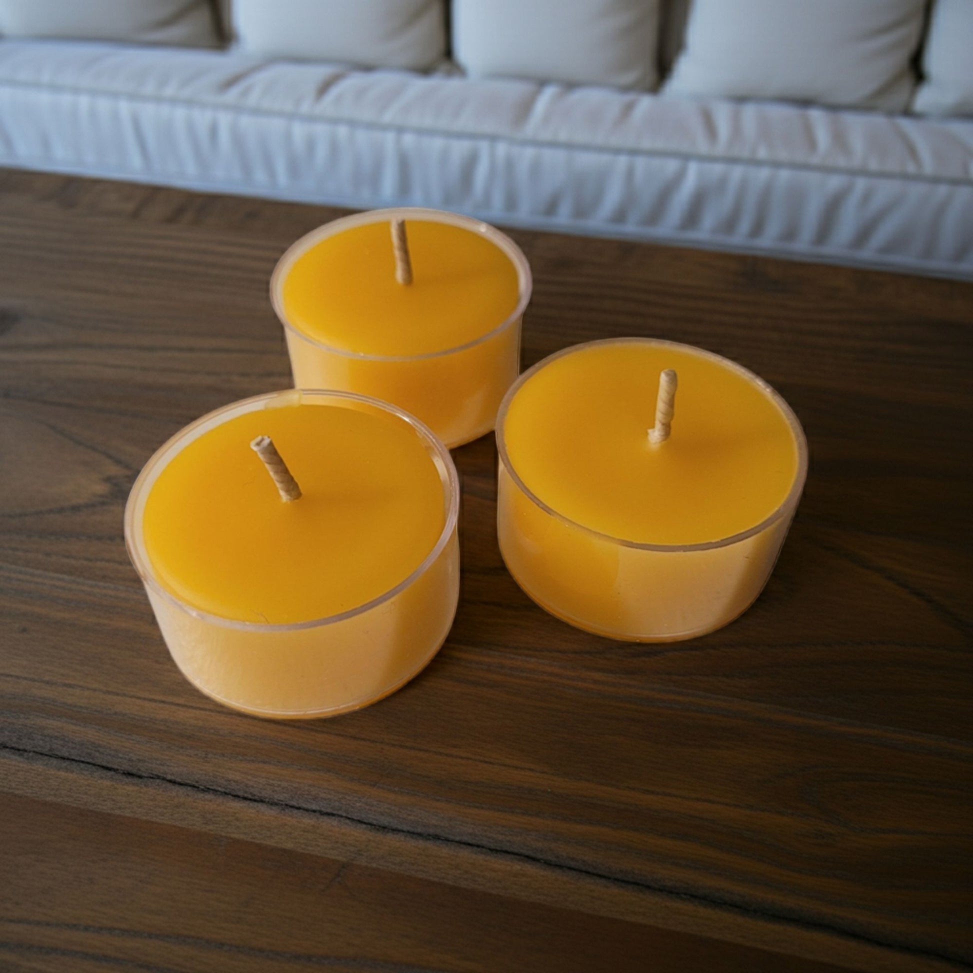 Three yellow candles on a wooden surface with a blurred background