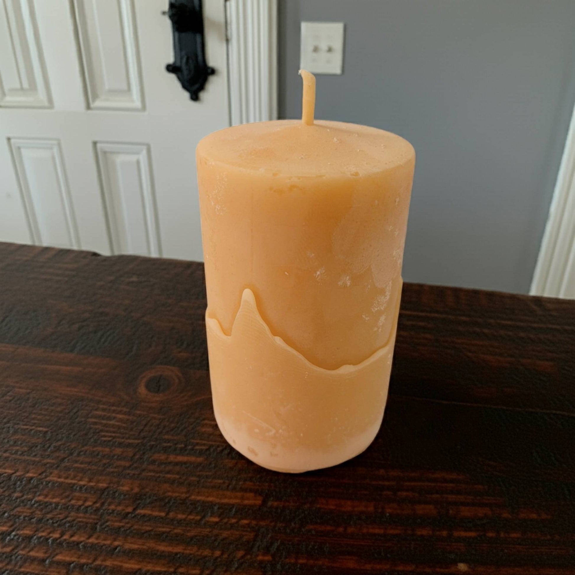 2x3 pillar beeswax candle on a wooden surface with a neutral background