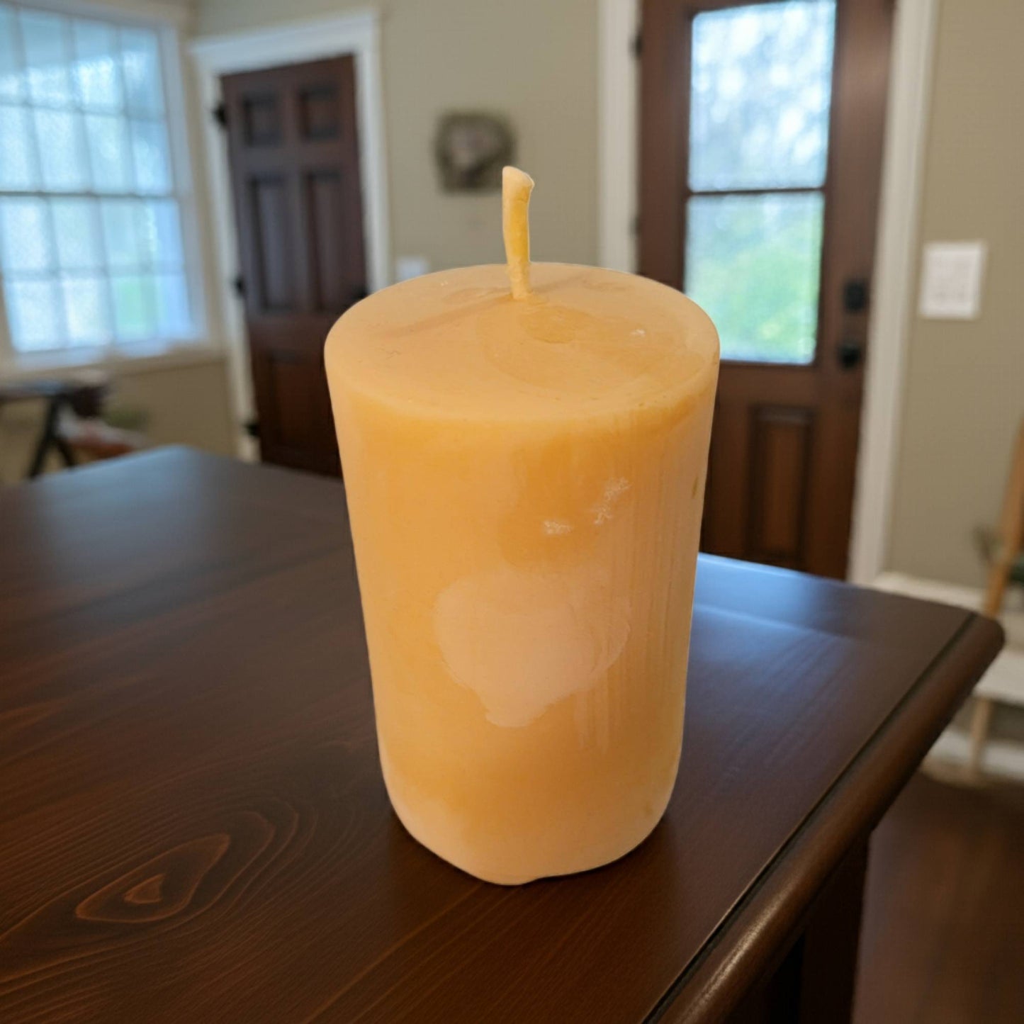 Beeswax Candle on a wooden table with a blurred indoor background