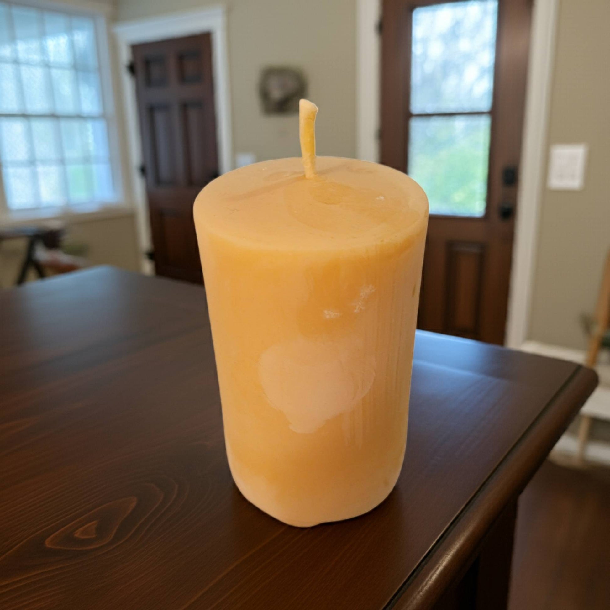 Beeswax Candle on a wooden table with a blurred indoor background