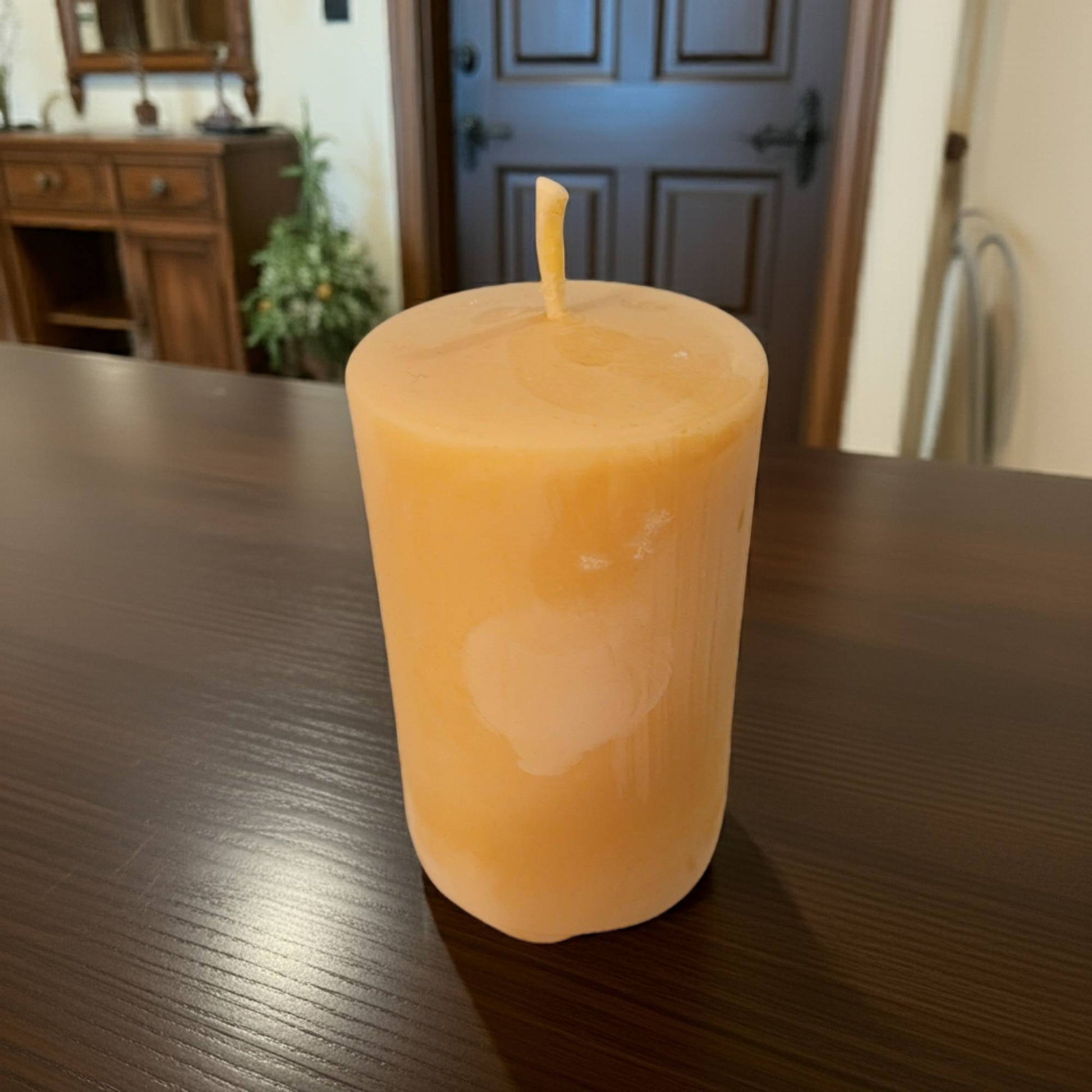 Smooth Pillar candle on a wooden table with a blurred background