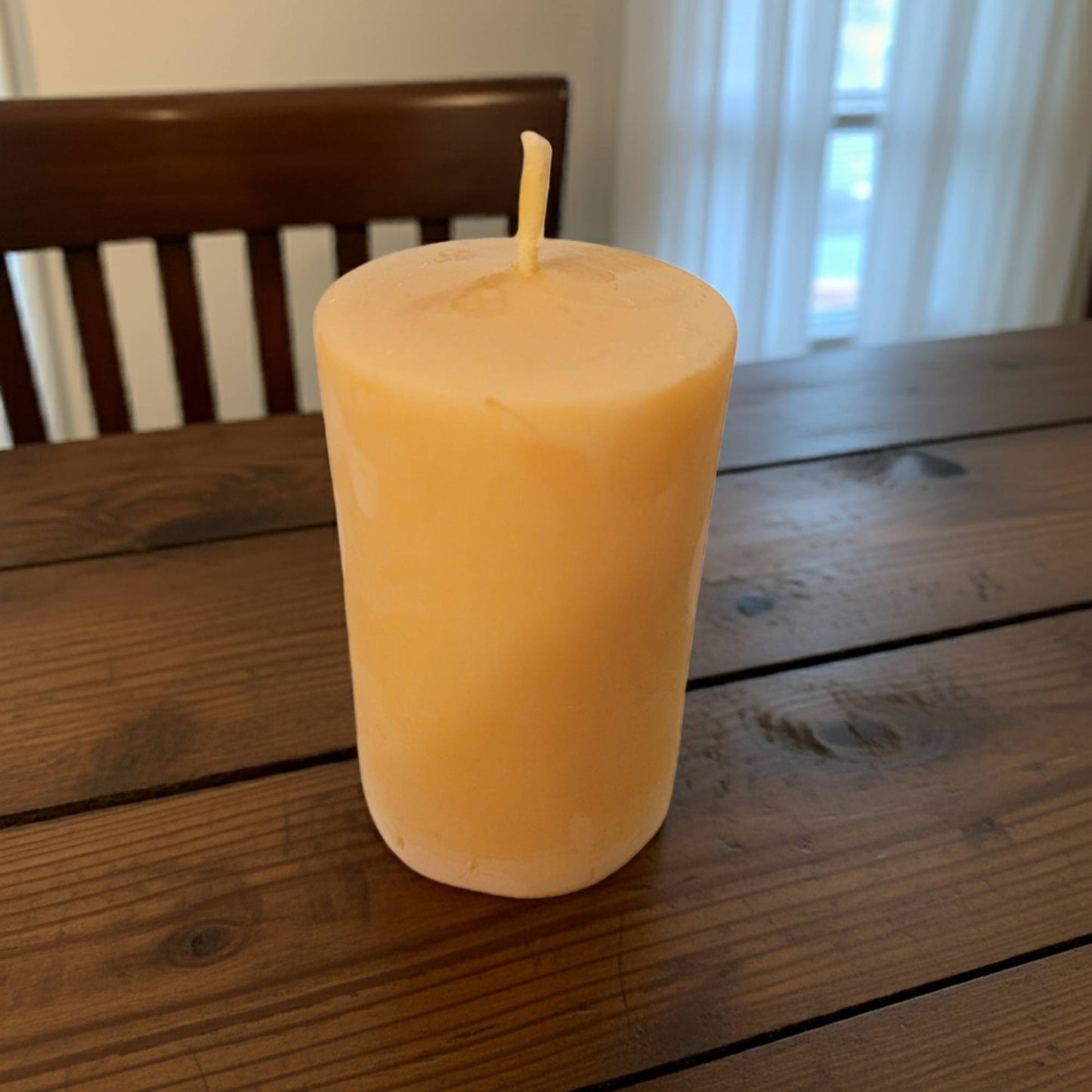 smooth pillar candle on a wooden table with a blurred background