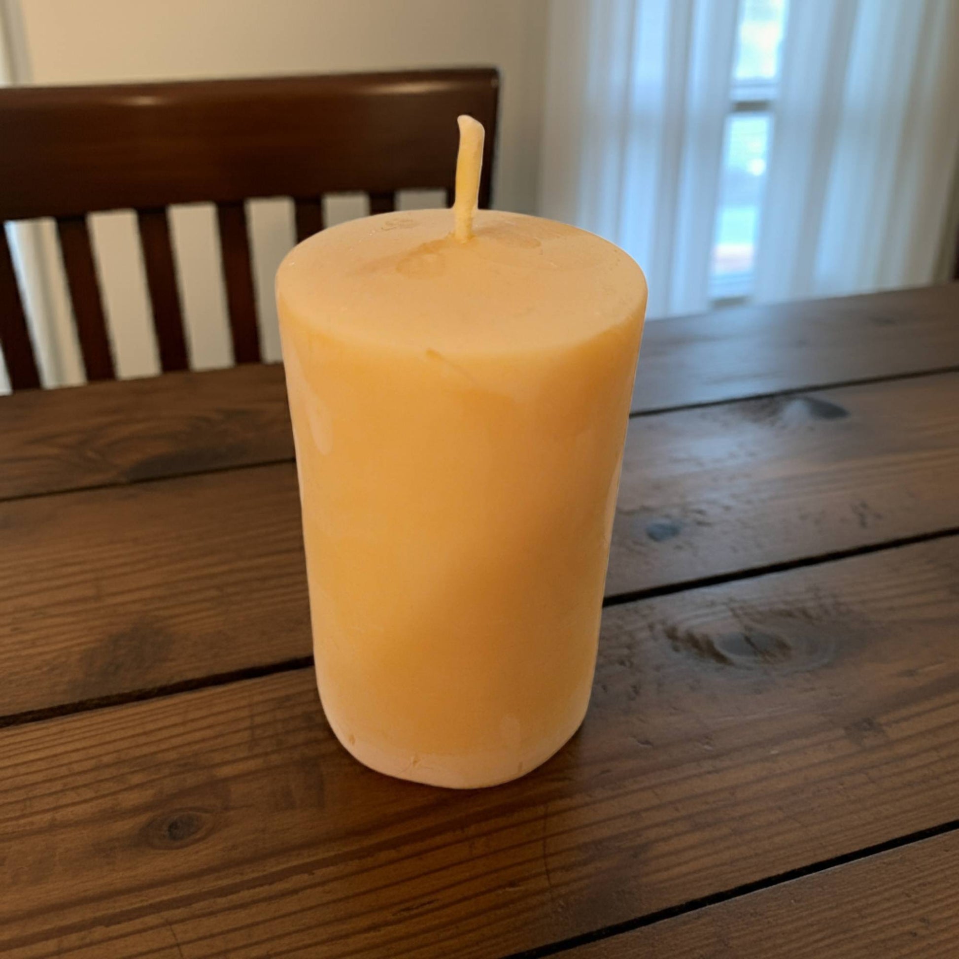 smooth pillar candle on a wooden table with a blurred background