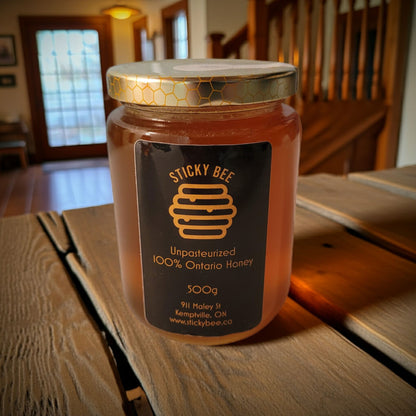 Jar of Sticky Bee honey on a wooden table with a home interior background