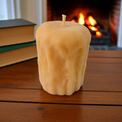 Rustic Pillar Candle on a wooden surface with a fireplace in the background