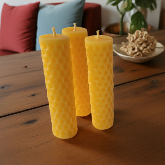 Three honeycomb textured candles on a wooden surface with a blurred background