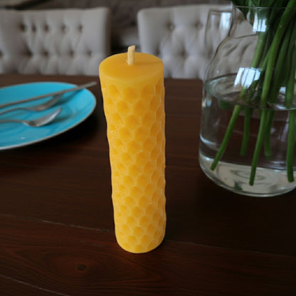 Pure beeswax honeycomb style candle on a wooden table with a blurred background