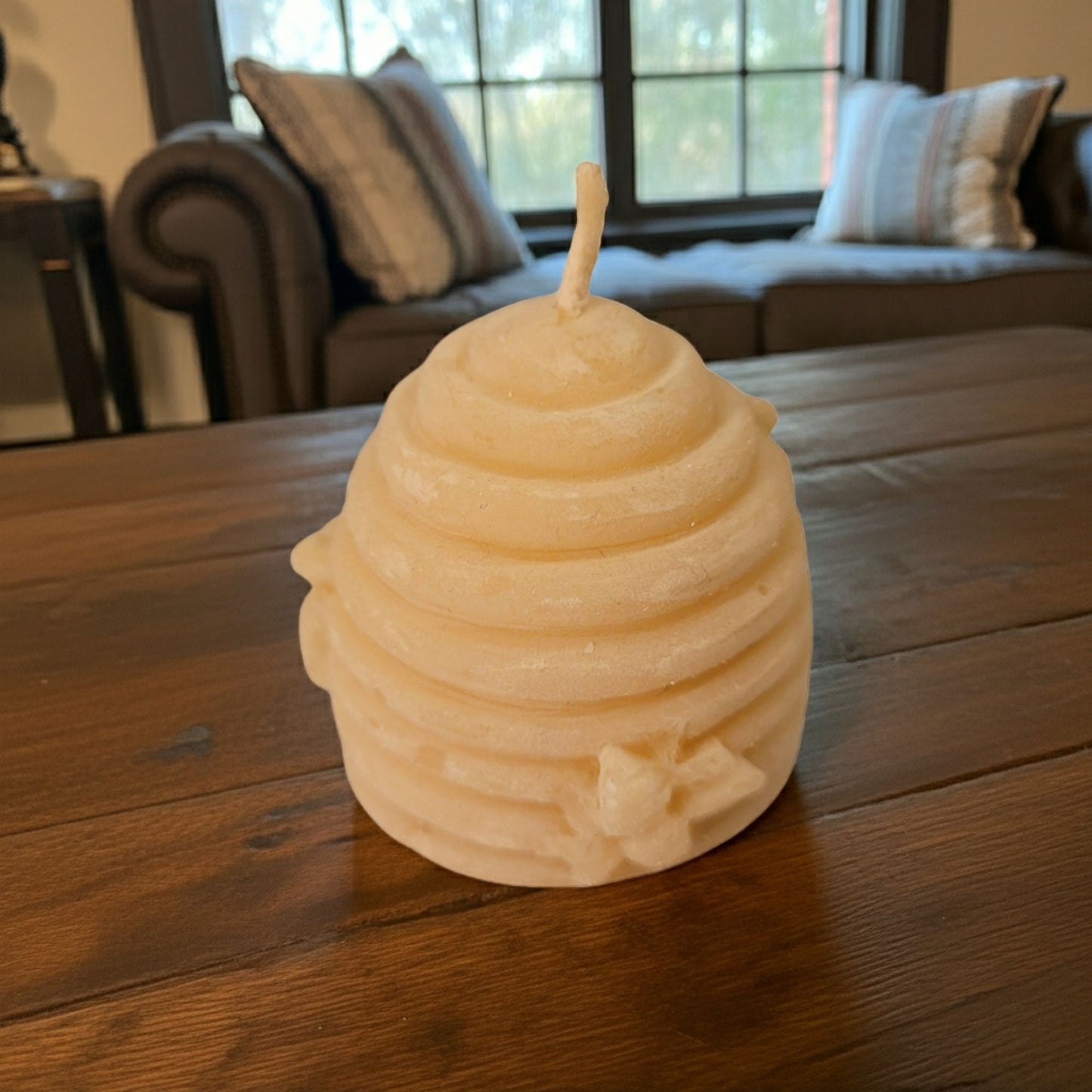 Beeswax honeycomb candle on a wooden table with a blurred background of a living room.