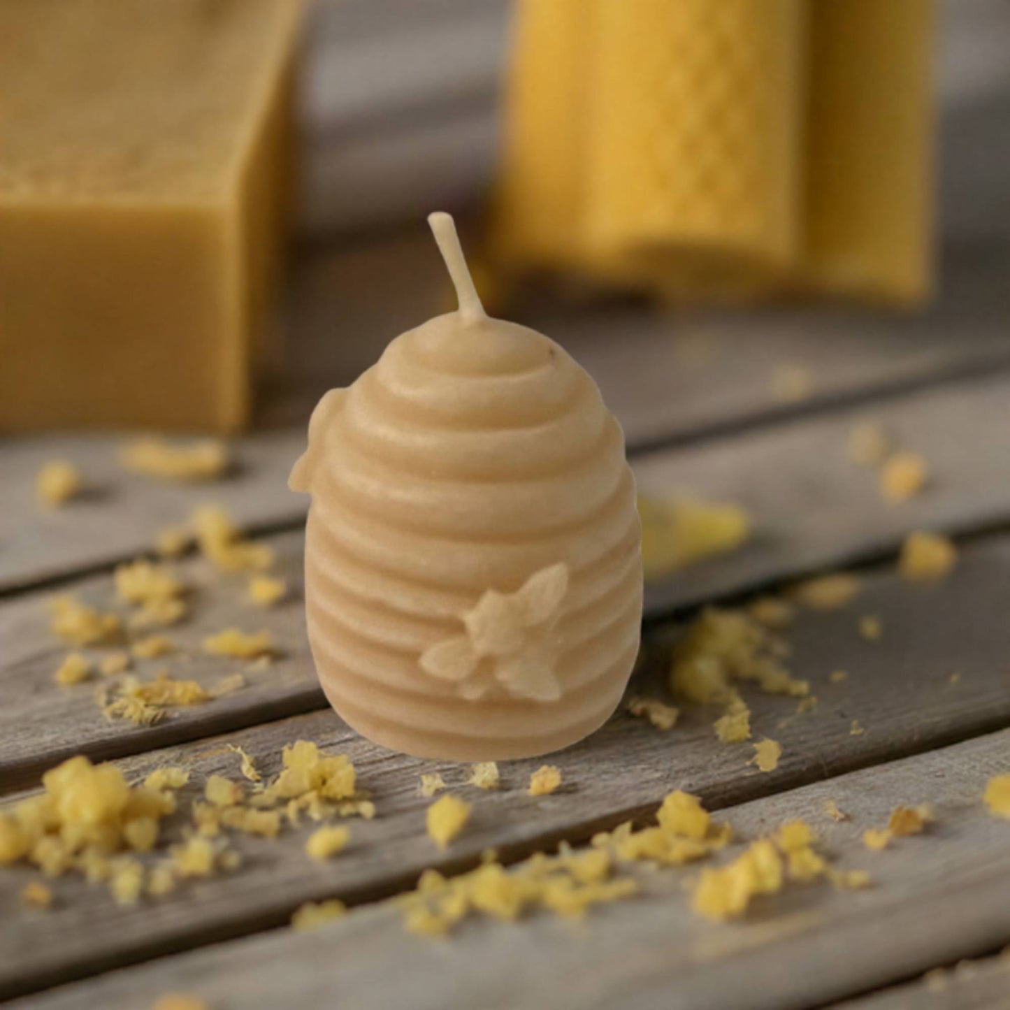 Beeswax candle shaped like a beehive with a honeybee on a wooden surface.
