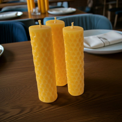 Natural beeswax candles on a wooden table with a blurred restaurant setting in the background.