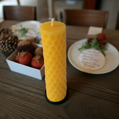 Honeycomb textured candle on a wooden table with decorative items in the background