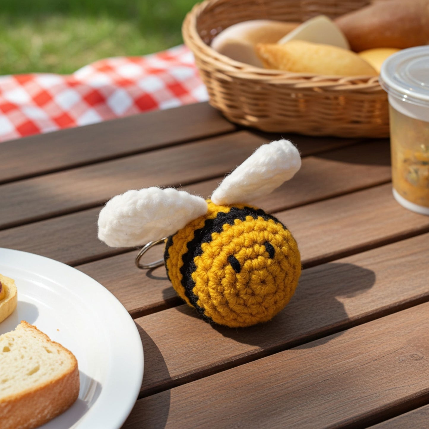 Crocheted bee keychain on a wooden table with bread and a basket in the background